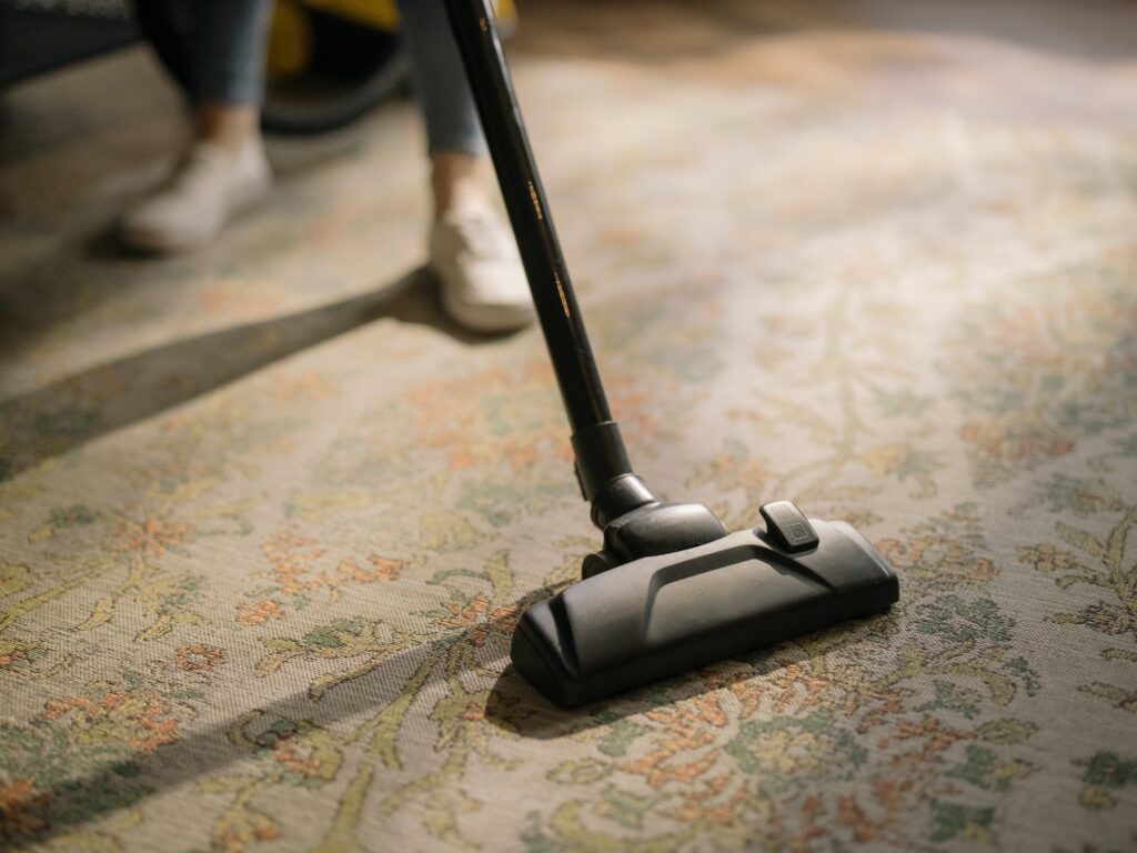 aspirateur entrain d'être passé sur tapis à motif fleuri